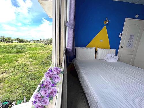een slaapkamer met een raam en een bed met paarse bloemen bij Happy Homestay in Budai