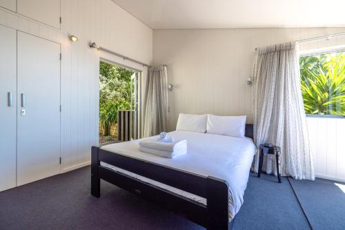 a bedroom with a bed with white sheets and a window at Black Bach in Onetangi