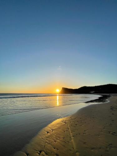 a beach with the sun setting in the distance at Casa Mariposa in Tola