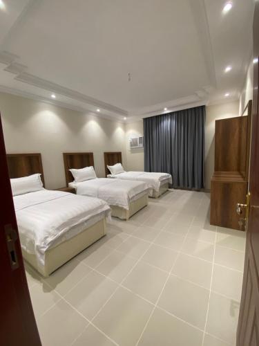 a hotel room with three beds and a window at قاردن وحدات سكنية خاصة in Al Madinah