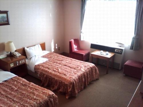a hotel room with two beds and a red chair at Onomichi View Hotel Seizan in Onomichi