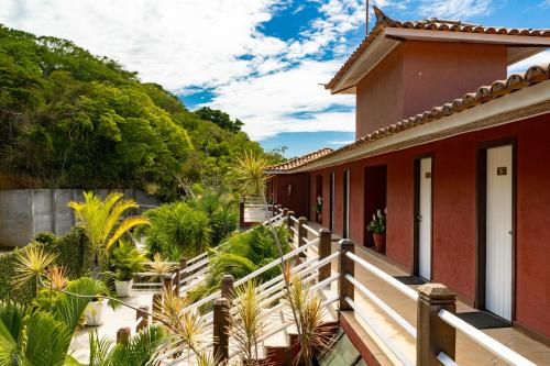 Riviera Búzios Hotel في بوزيوس: منزل مع شرفة خشبية مع نباتات وأشجار