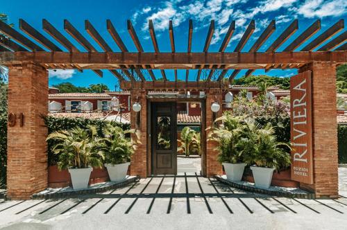 Riviera Búzios Hotel في بوزيوس: مدخل إلى مبنى من الطوب مع نباتات الفخار