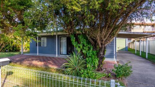 a blue house with a tree and a fence at Dog Friendly Holiday House In Bongaree in Bongaree