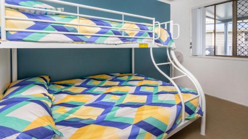 a bedroom with a bunk bed with a colorful comforter at Dog Friendly Holiday House In Bongaree in Bongaree