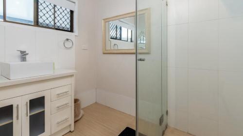 a bathroom with a shower and a sink and a mirror at Dog Friendly Holiday House In Bongaree in Bongaree