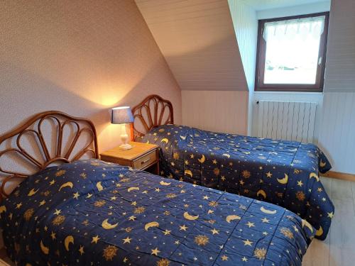 a attic bedroom with two beds and a window at Holiday Home by Roscoff Beach and Horse Racing in Plouescat