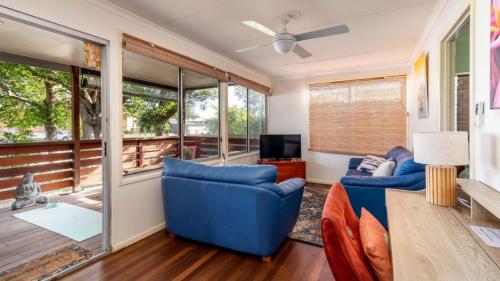 a living room with two blue chairs and a television at Pet Friendly Cottage With Waterviews in Bongaree