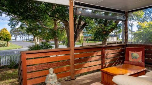 a porch with a bench and a table at Pet Friendly Cottage With Waterviews in Bongaree