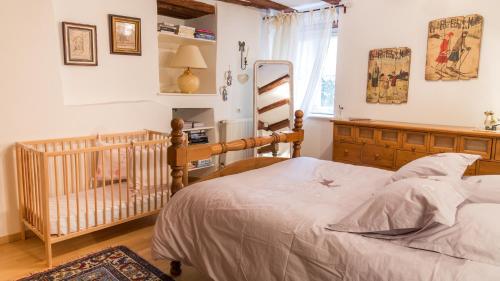 a bedroom with a bed and a crib in it at La Maison des Tanneurs in Ribeauvillé
