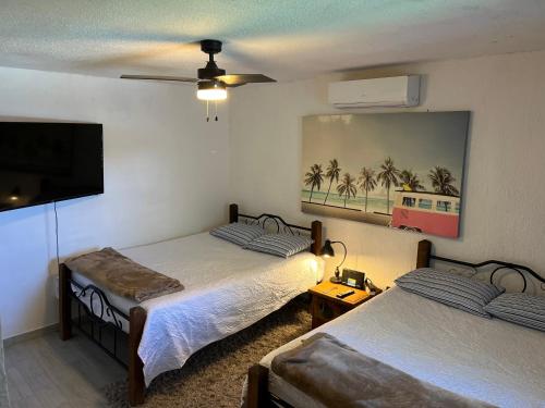 a bedroom with two beds and a flat screen tv at Casa Manila ALBERCA TERRAZA Y ACCESO A PLAYA in Bahía Kino