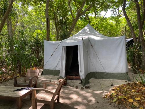 a tent with a table and chairs in a yard at Camp Tarimbang in Tandulujangga