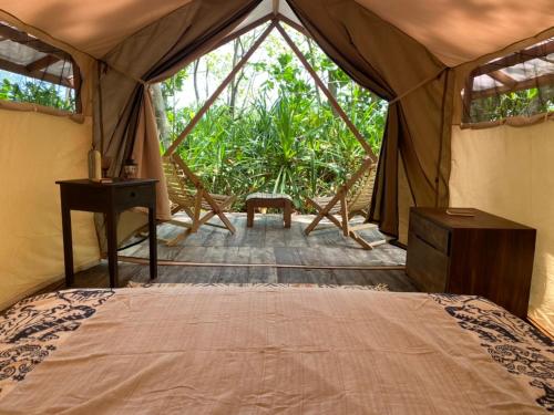 TandulujanggaにあるCamp Tarimbangのテント内のベッドルーム(ベッド1台、デスク付)