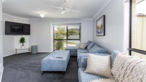 a living room with a blue couch and a table at Family Holiday Home At Sandstone Point in Sandstone Point