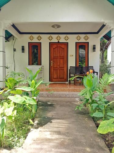 a front porch of a house with a wooden door at Follow The Rabbit Bungalow in Gili Air