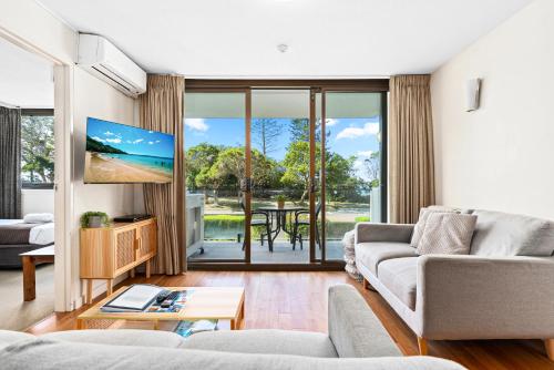 a living room with a couch and a tv at Windward Apartments in Mooloolaba