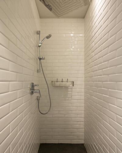 a bathroom with a shower in a white tiled wall at Hotel Altiplanico Bellas Artes in Santiago
