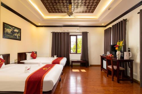 a hotel room with two beds and a table at Little Town Villa in Hoi An