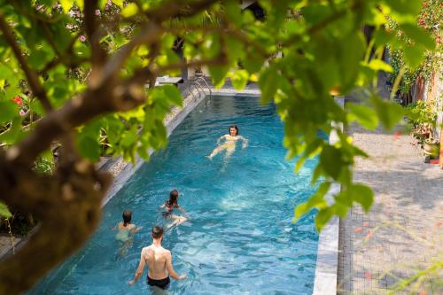 a group of people swimming in a swimming pool at Little Town Villa in Hoi An