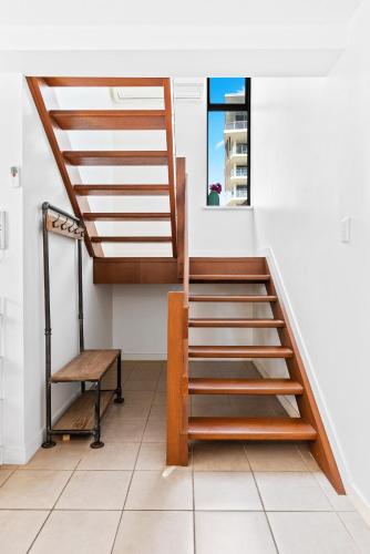 a staircase in a room with a table and a bench at Windward Apartments in Mooloolaba