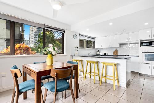 a kitchen with a wooden table and chairs at Windward Apartments in Mooloolaba