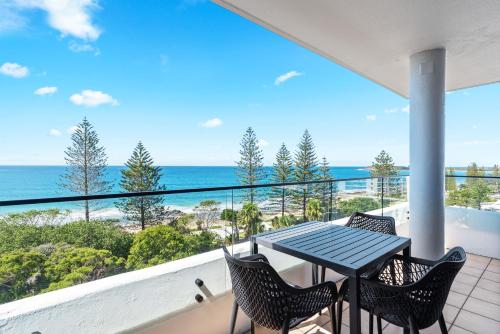 a balcony with a table and chairs and the ocean at Windward Apartments in Mooloolaba