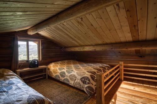 um quarto num chalé de madeira com uma cama e uma janela em The Raven's Nest Resort & Campground em Fairmont Hot Springs