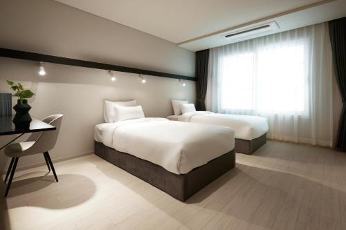 a hotel room with two beds and a desk at The Connoisseur Residence Hotel in Seoul