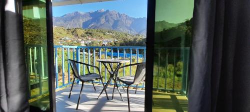 a balcony with a table and chairs and a view of a mountain at Wind Valley Farmstay in Kundasang