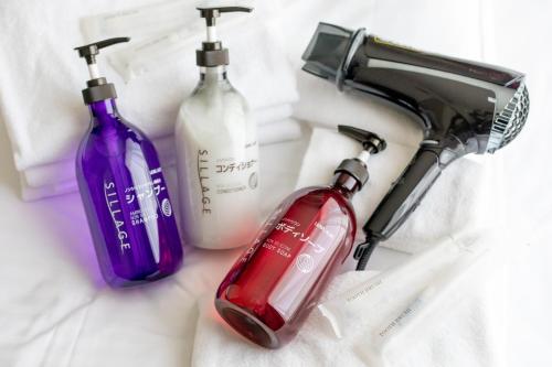 three bottles of soap and a blow dryer on a counter at Oyado Nishishichijo in Kyoto