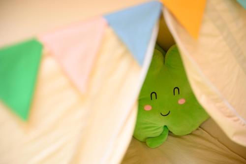 a green pillow with a smiley face sticking out from a sheet at 貸温泉別荘Clover天城杉のログハウス伊豆高原 in Ito