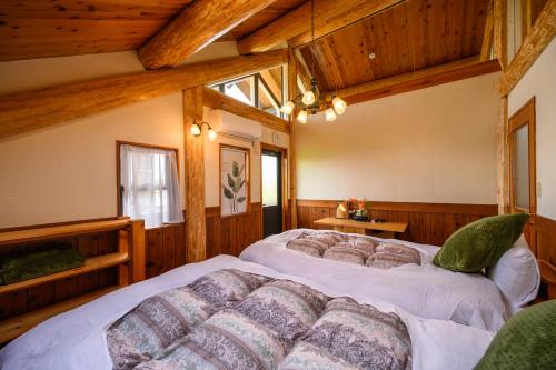 2 camas en una habitación con paredes de madera en 貸別荘Clover　天城杉のログハウス　伊豆高原, en Ito