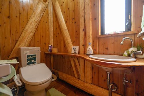 a wooden bathroom with a toilet and a sink at 貸温泉別荘Clover天城杉のログハウス伊豆高原 in Ito