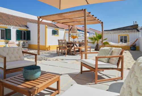 eine Terrasse mit Stühlen, einem Tisch und einem Sonnenschirm in der Unterkunft Comporta Sandy Villa, By TimeCooler in Comporta