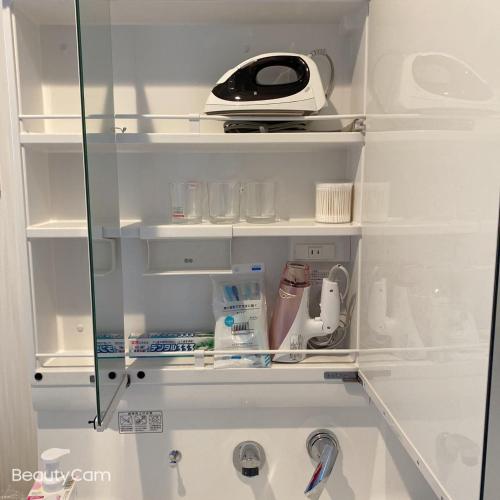 a glass cabinet with a appliance in a kitchen at ALL TRUST2馆临近心斋桥道頓堀难波直达梅田关西机场Usj全新独栋别墅四个卧室可住8人超大空间3卫2浴厨房设施齐全电视冰箱洗衣机空调配置齐全免费停车4分钟步行至今宫站 in Osaka