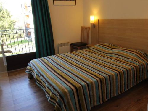 a hotel room with a bed with a striped blanket at Appartement Bagnères-de-Luchon, 2 pièces, 4 personnes - FR-1-313-222 in Luchon