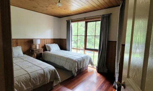 a bedroom with two beds and a large window at Tall Trees Eco Retreat - Fern Cottage in Apollo Bay