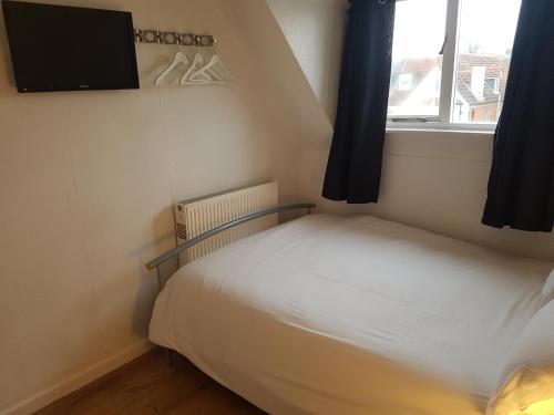 a small bedroom with a bed and a tv on the wall at Boscombe Reef Hotel in Bournemouth