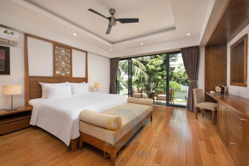 um quarto com uma grande cama branca e uma secretária em Ocean Villas Da Nang em Da Nang