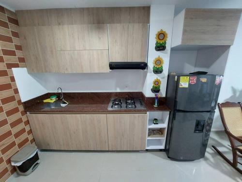 a small kitchen with a stove and a refrigerator at Hermoso Apartamento Cerca a la Playa Puerto Colombia in Puerto Colombia