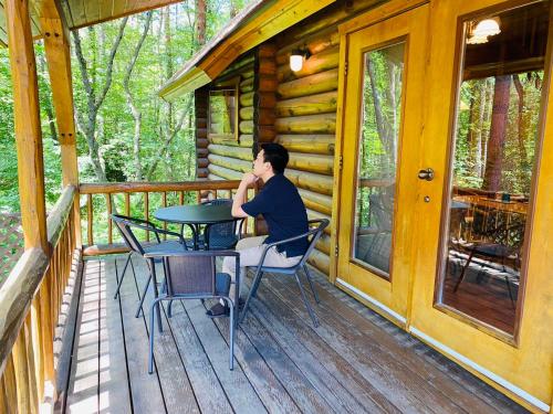 een man aan een tafel op de veranda van een hut bij HOLIDAY VILLA Hotel & Resort KARUIZAWA in Tsumagoi