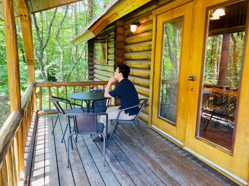 un homme assis à une table sur le porche d'une cabane dans l'établissement HOLIDAY VILLA Hotel & Resort KARUIZAWA, à Tsumagoi