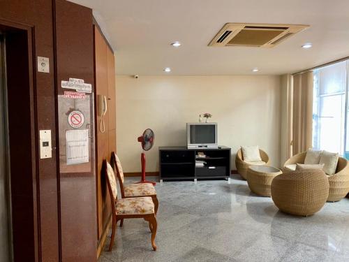ein Wohnzimmer mit einem TV, einem Sofa und Stühlen in der Unterkunft Wantana Mansion in Hat Yai