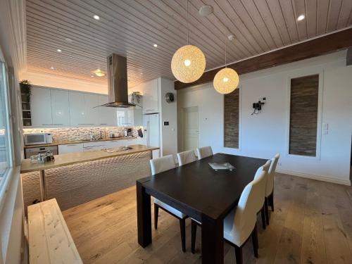 une cuisine et une salle à manger avec une table noire et des chaises blanches dans l'établissement Stunning 5BR 16 Bed Home with Finnish Sauna & Jacuzzi 340 m2, à Tampere