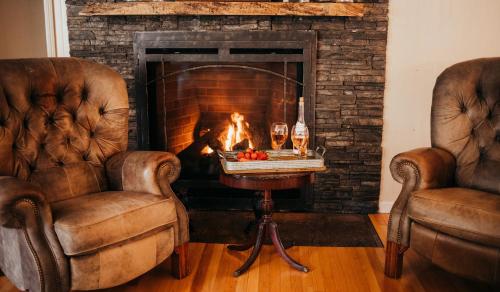 two chairs and a fireplace with a table with fruit on it at Taylor Creek Lodge in Gold Beach