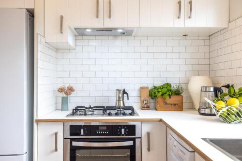 eine Küche mit weißen Schränken und einem Herd mit Backofen in der Unterkunft Ocean Breeze Cottage - Coast & Country in Onetangi