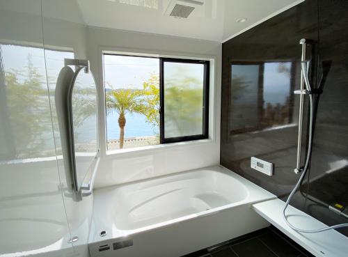 een badkamer met een wit bad en een raam bij 天草VIVID V2 in Kami Amakusa