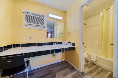 bagno con lavandino, servizi igienici e specchio di Catalina Motel a Corpus Christi