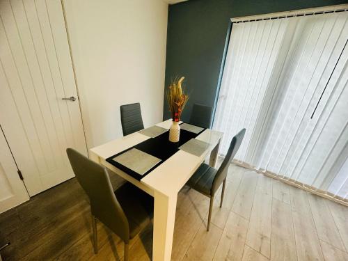 a dining room table with chairs and a vase on it at Hemel Apartments - Hemel Haven in Hemel Hempstead