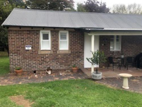 a brick house with a cat sitting in the yard at The Stables in Armidale